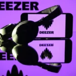 This photograph taken on January 13, 2025 in Toulouse shows headphones beside a smartphone and a computer screen displaying the logo of the French music streaming platform Deezer.